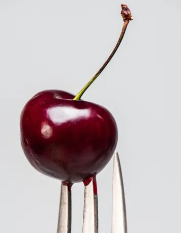 A juicy cherry on a silver fork
