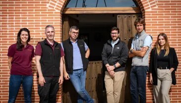 El equipo de Bodega Numanthia posando frente a la bodega en la región de Toro, España, representando a las personas apasionadas detrás de la reconocida producción vinícola.
