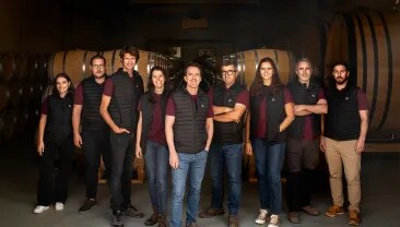 El equipo de Bodega Numanthia posando frente a la bodega en la región de Toro, España, representando a las personas apasionadas detrás de la reconocida producción vinícola.