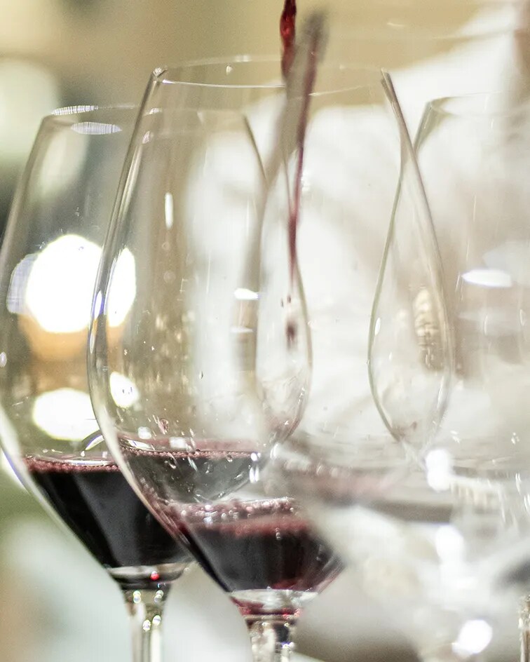 Primer plano de vino tinto sirviéndose en una copa durante una sesión de cata, destacando el color y la textura ricos del vino, resaltando la experiencia de saborear los vinos tintos españoles de Bodega Numanthia de la región de Toro.